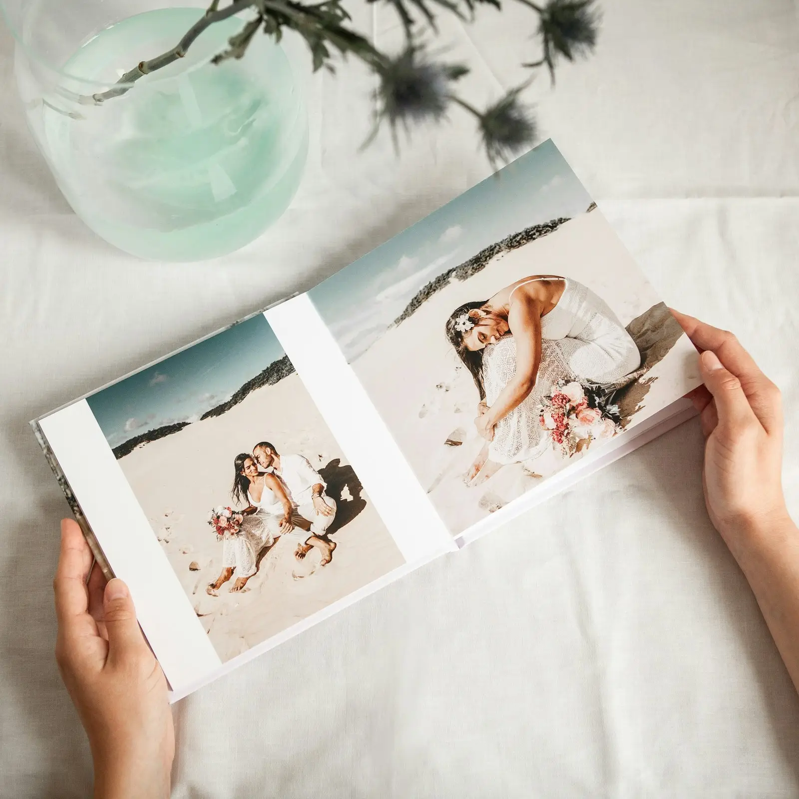 Open wedding photo book showing a couple photographed on a beach