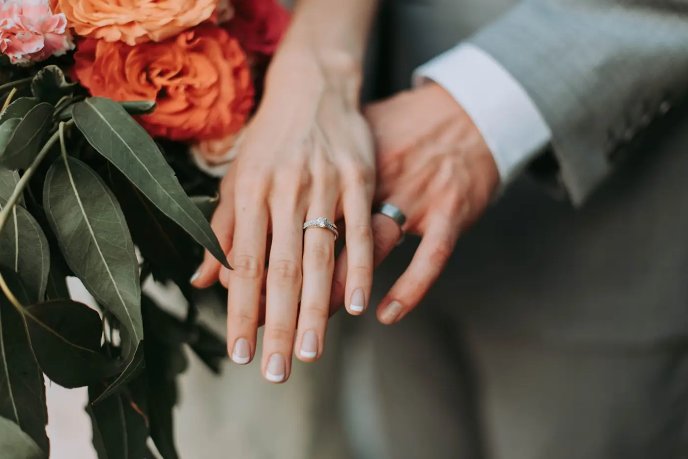 Wedding couple showing their rings beside a bouquet
