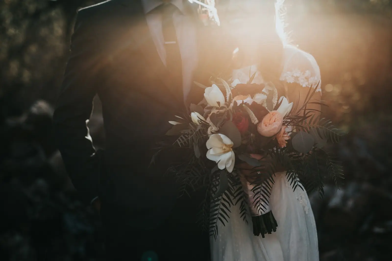 Newly married couple holding a bouquet in warm evening light
